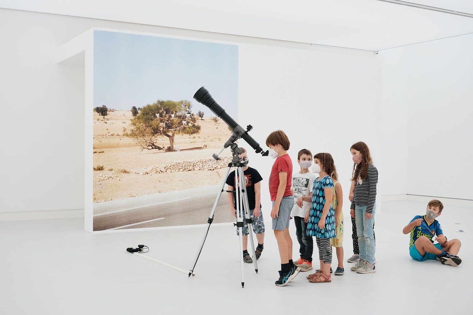 Kinder stehen vor einem Fernrohr.