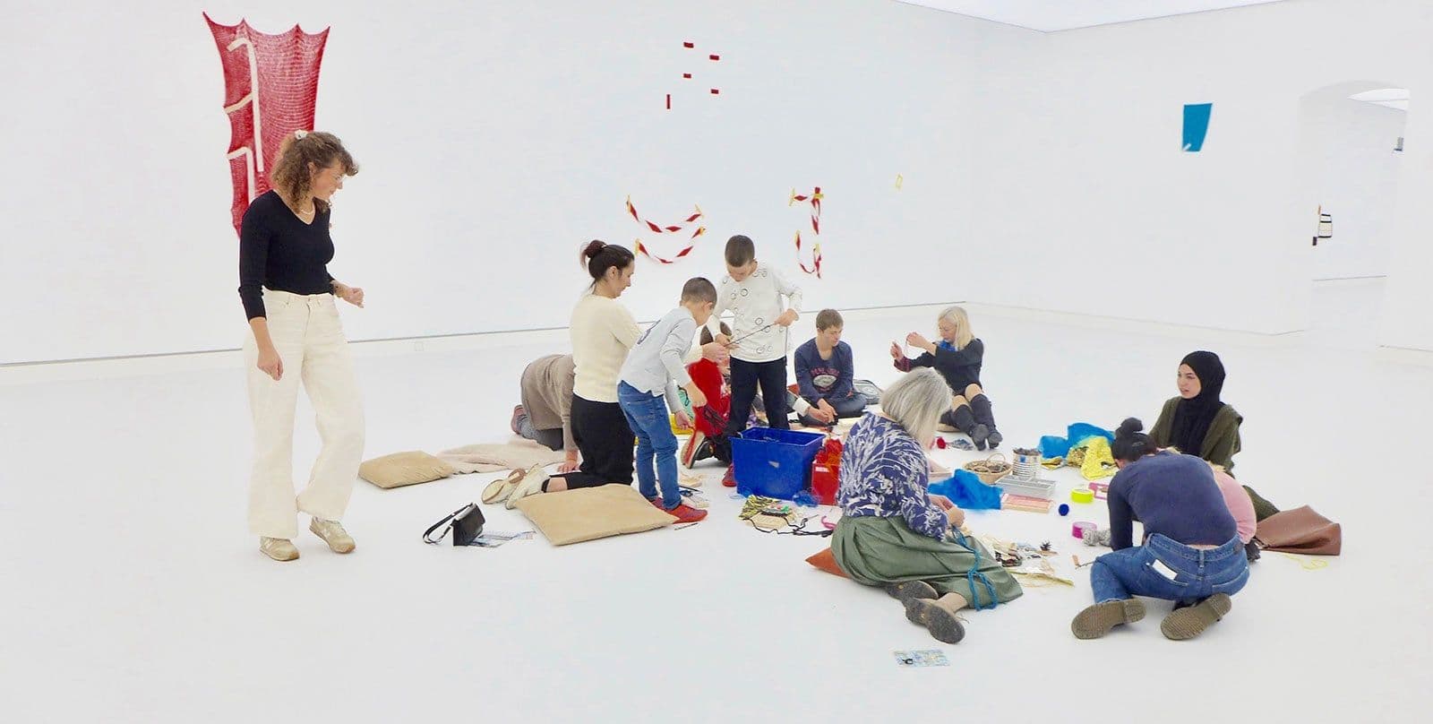 Eine Gruppe von Menschen sitzt auf dem Boden. Alle basteln gemeinsam etwas.